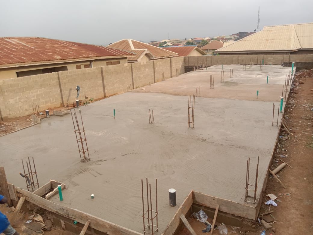 Cast concrete foundation slab with reinforcement bars and green service pipes