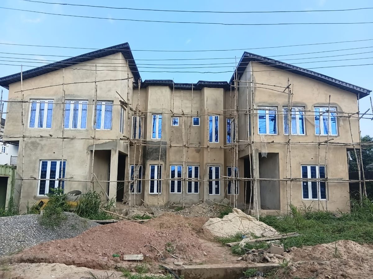 Plastered two-storey building with installed windows and roof covering, bamboo scaffolding still in place